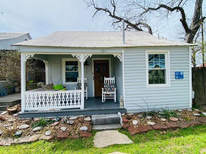 The New Braunfels Cottage at Comal Inn, a historic cottage with a white front porch and rocking chairs